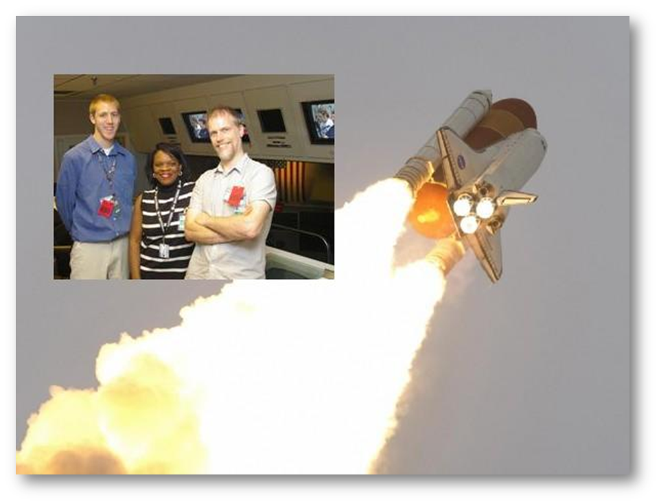 Space shuttle launching with two men posing in front of a model shuttle.