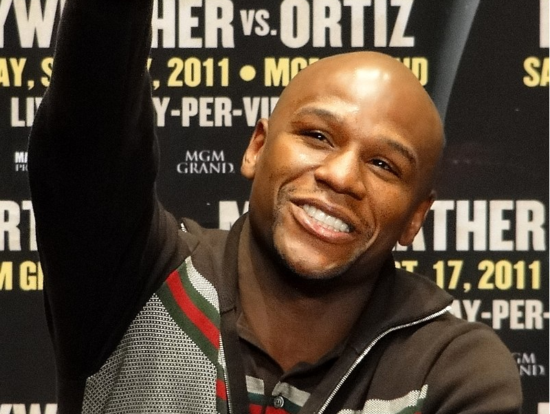 Smiling man at a press event with promotional text in the background.