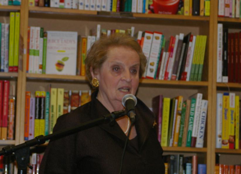 Woman speaking into a microphone at a bookstore event.