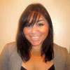 Smiling woman with dark hair and bangs in a gray top.